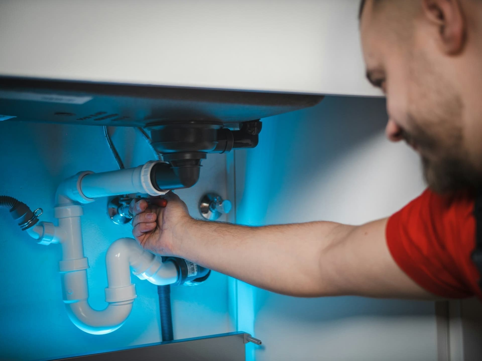 Plumber working on a supply pipe in a wall