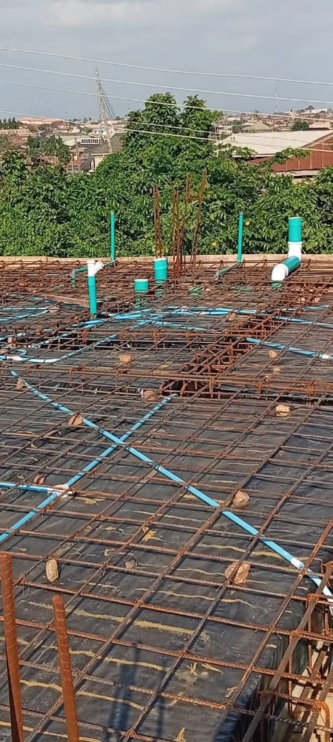 Blue and green pipework set out across the steel reinforcement of an upper floor slab